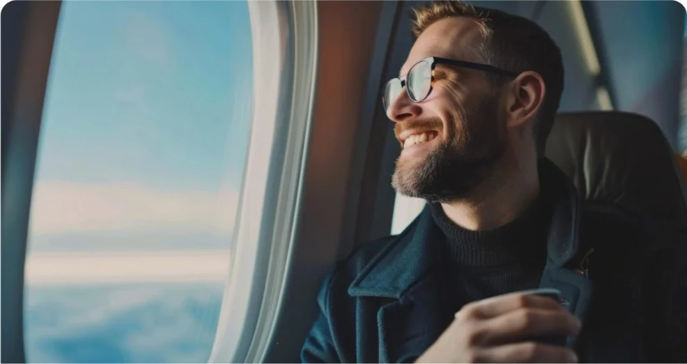 Imagem ilustrativa de um homem sorrindo junto à janela de um avião.